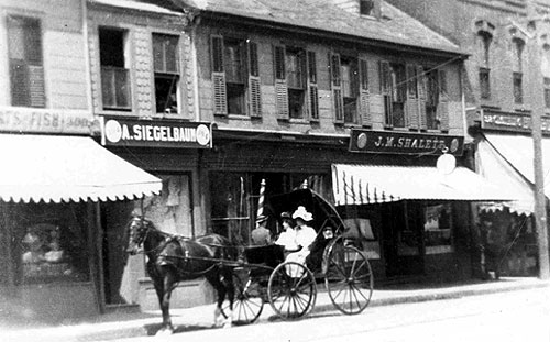 Main Street, July 1907. Two ladies in their carriage admire the finery in Siegelbaum's window.